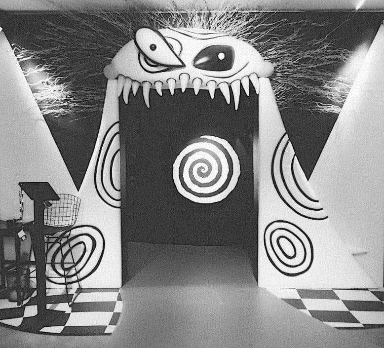 um rosto com cabelo espetado que cobre uma parede
a boca desse rosto é uma porta